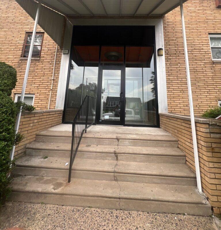 Glass storefront entrance at the top of an apartment building stairway